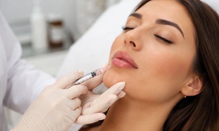 Primo piano di un trattamento di filler labbra con acido ialuronico eseguito da un professionista di medicina estetica in un ambiente clinico.